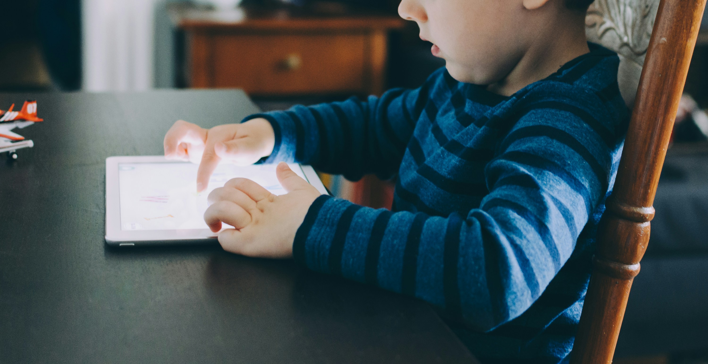 A child using a tablet at a wooden table